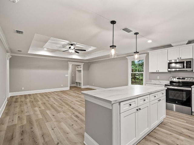 kitchen featuring stainless steel appliances, a raised ceiling, ceiling fan, white cabinets, and a center island