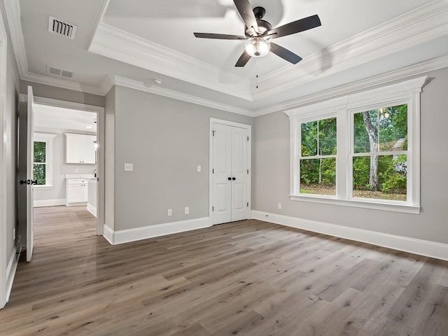 unfurnished bedroom featuring a tray ceiling, ceiling fan, dark hardwood / wood-style flooring, and ornamental molding