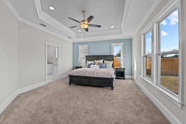 bedroom with connected bathroom, ornamental molding, ceiling fan, a tray ceiling, and light carpet