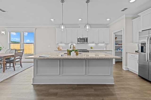 kitchen featuring hanging light fixtures, a center island with sink, white cabinets, and appliances with stainless steel finishes