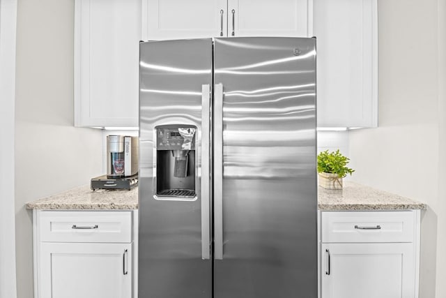 kitchen with white cabinetry, light stone countertops, and stainless steel fridge