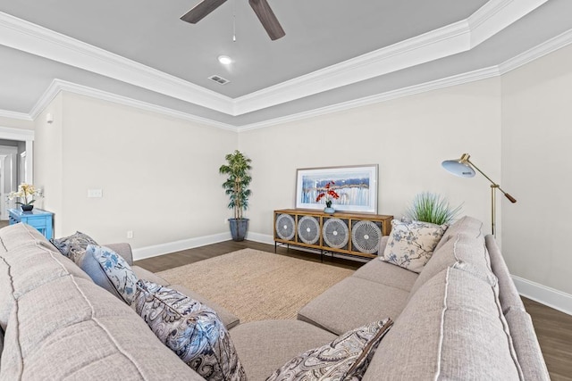 living room featuring dark hardwood / wood-style flooring, crown molding, a tray ceiling, and ceiling fan