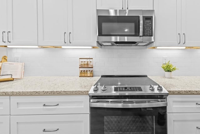 kitchen featuring light stone counters, stainless steel appliances, decorative backsplash, and white cabinets