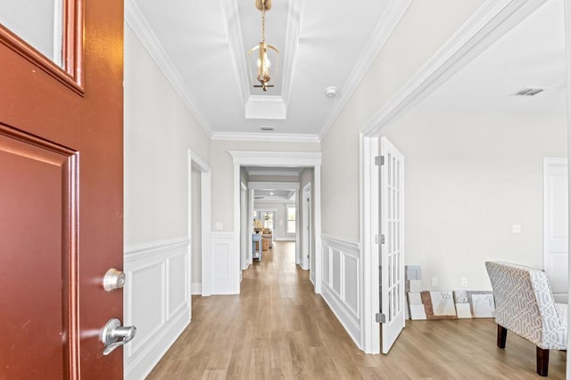 hall with ornamental molding and light hardwood / wood-style floors