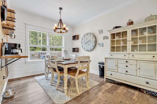 dining room with an inviting chandelier, crown molding, hardwood / wood-style flooring, and wooden walls