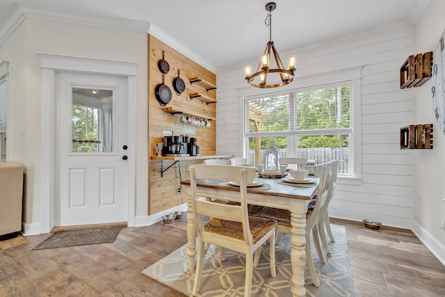 dining area featuring crown molding, wood walls, and an inviting chandelier