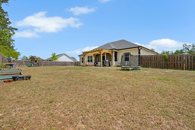 rear view of house with a fenced backyard, a trampoline, a yard, and a pergola