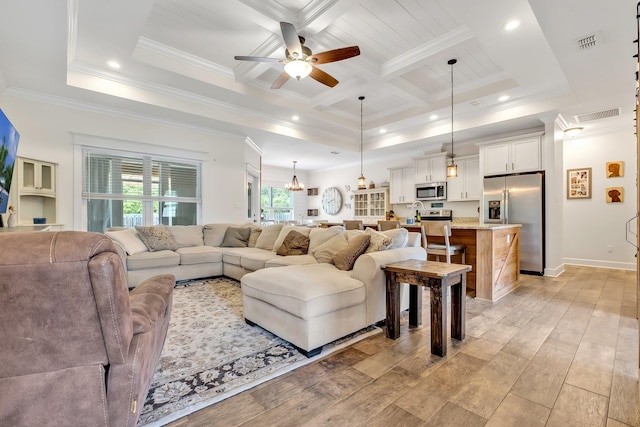 living area featuring visible vents, crown molding, ceiling fan, and light wood-type flooring