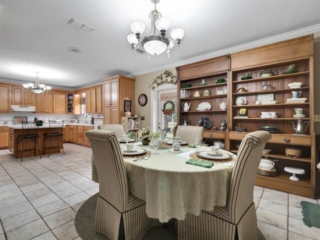 tiled dining space with a chandelier and crown molding