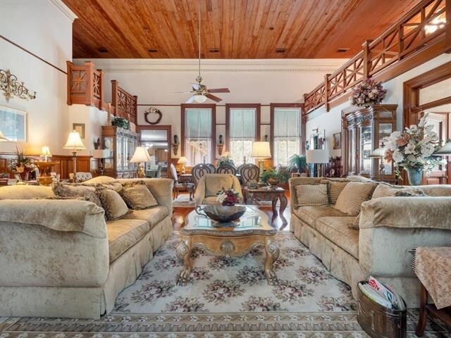 living room with ceiling fan, crown molding, and wood ceiling