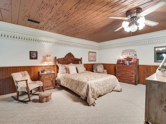 carpeted bedroom featuring wood walls, ceiling fan, crown molding, and wooden ceiling