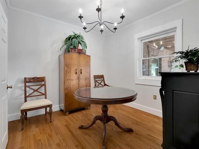 living area with ornamental molding, light hardwood / wood-style floors, and a notable chandelier