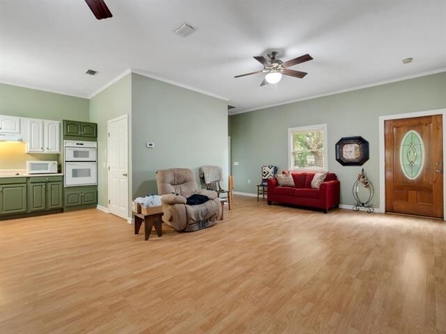 living room with light hardwood / wood-style floors, ceiling fan, and crown molding