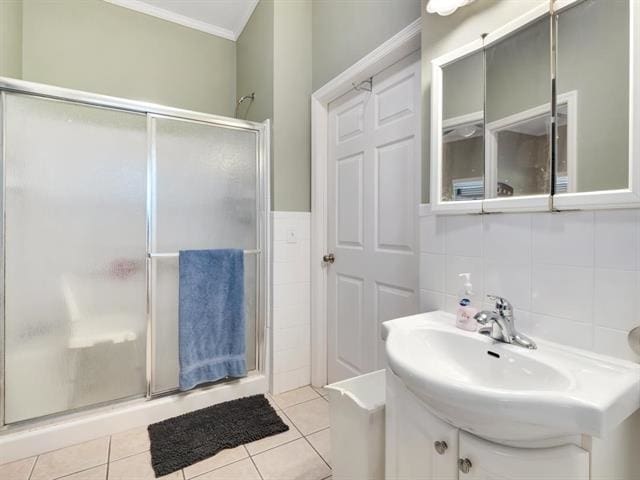 bathroom featuring tile patterned floors, ornamental molding, backsplash, sink, and a shower with shower door