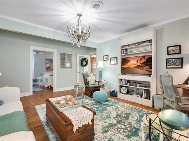 living room featuring dark hardwood / wood-style floors, an inviting chandelier, and ornamental molding