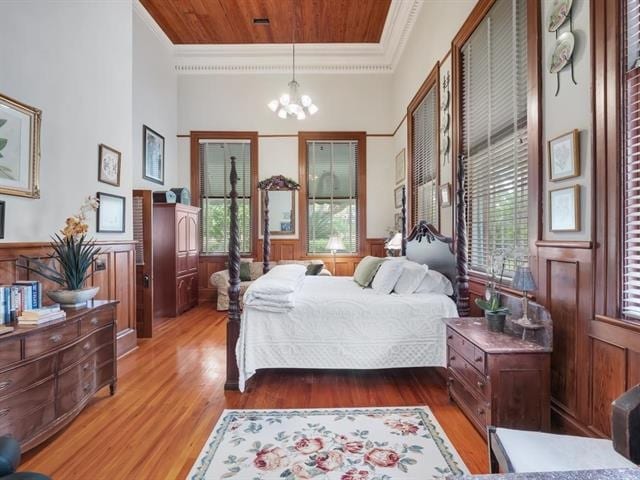 bedroom with wood-type flooring, multiple windows, a chandelier, and ornamental molding