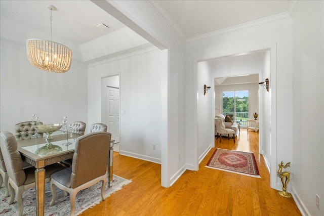 dining area featuring hardwood / wood-style flooring, an inviting chandelier, and crown molding