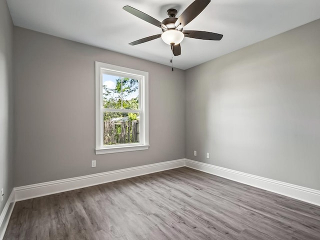 empty room with a ceiling fan, baseboards, and wood finished floors