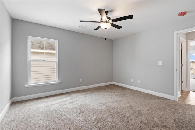 spare room featuring visible vents, carpet floors, baseboards, and a ceiling fan