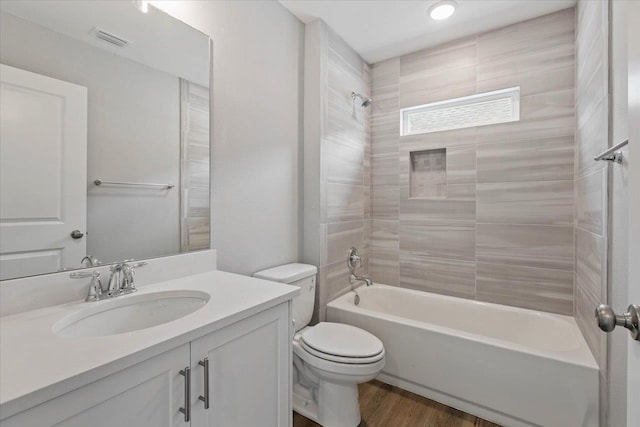 bathroom with vanity, wood finished floors, visible vents, toilet, and shower / bathtub combination