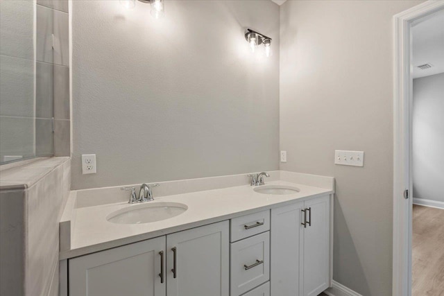 full bath with a sink, visible vents, baseboards, and double vanity