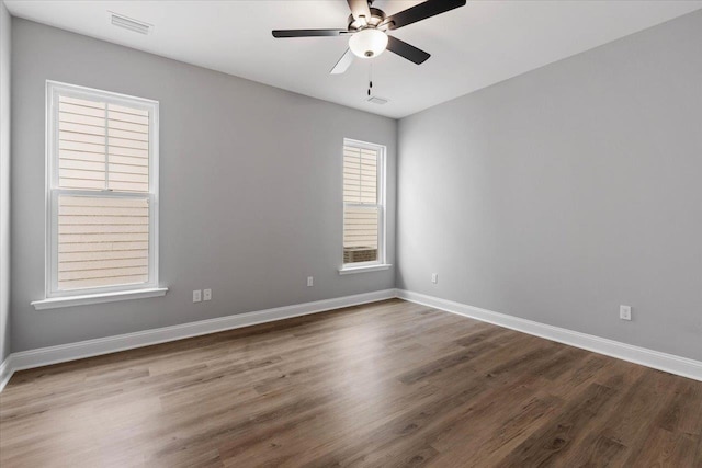 spare room with visible vents, baseboards, dark wood-style flooring, and ceiling fan