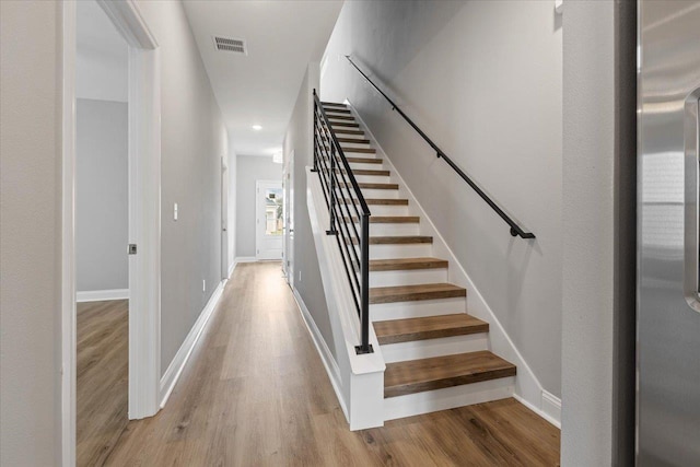 stairs featuring visible vents, baseboards, and wood finished floors