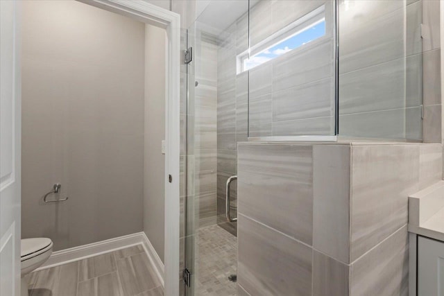 full bathroom featuring vanity, a shower stall, toilet, and baseboards