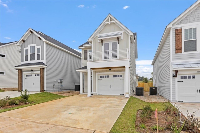 beach home featuring a balcony, central AC unit, concrete driveway, a garage, and board and batten siding