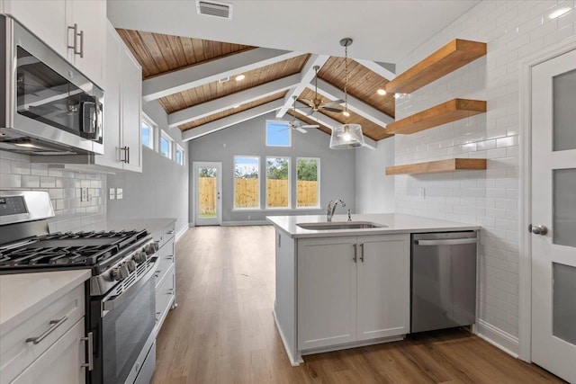 kitchen featuring visible vents, a sink, wood finished floors, stainless steel appliances, and open shelves