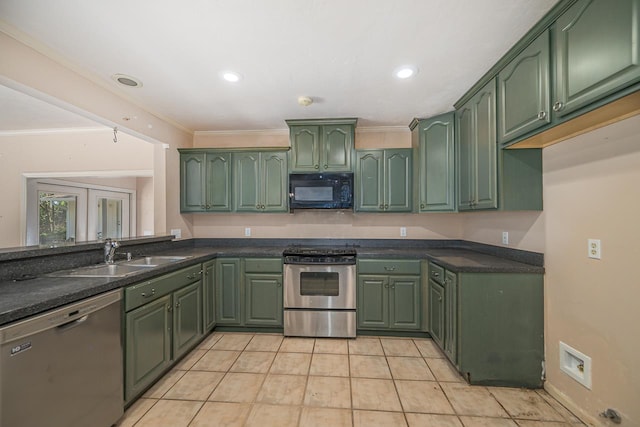 kitchen featuring dark countertops, appliances with stainless steel finishes, crown molding, green cabinets, and a sink