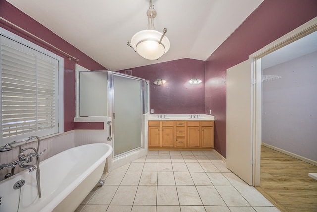 full bathroom with lofted ceiling, tile patterned flooring, a sink, a freestanding bath, and a shower stall