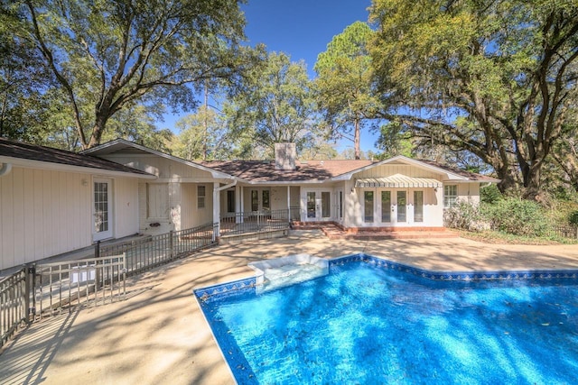 pool with french doors, a patio area, and fence