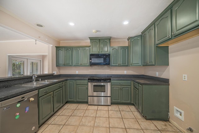 kitchen with stainless steel appliances, a sink, green cabinets, dark countertops, and crown molding