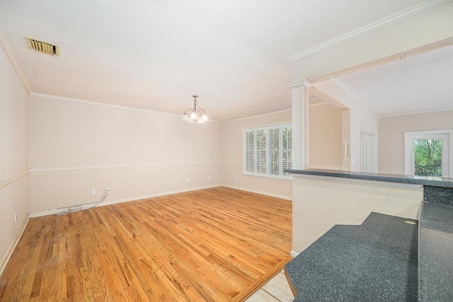 interior space with a chandelier, ornamental molding, wood finished floors, and visible vents