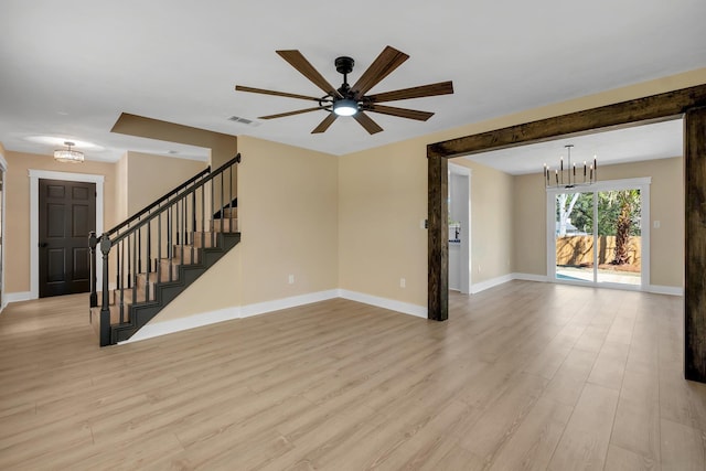 empty room featuring light wood-type flooring, baseboards, stairs, and visible vents