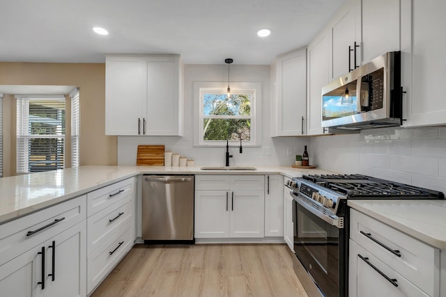 kitchen featuring appliances with stainless steel finishes, a sink, and white cabinetry