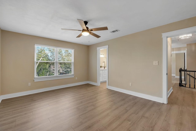 empty room featuring light wood-style floors, visible vents, baseboards, and a ceiling fan