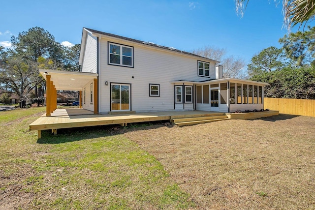 rear view of property featuring a yard, a sunroom, fence, and a wooden deck