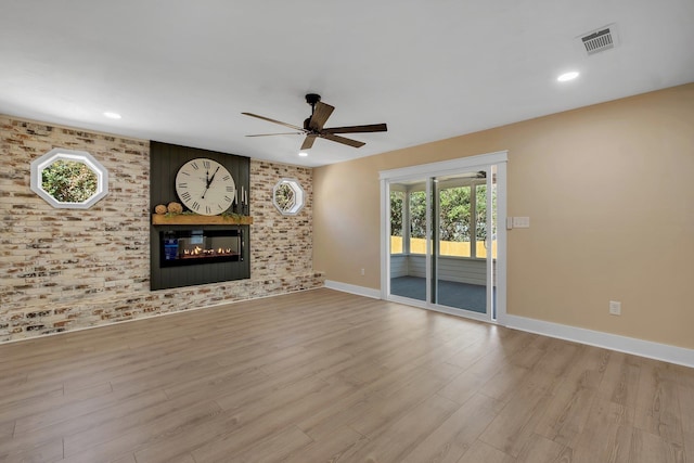 unfurnished living room featuring ceiling fan, visible vents, baseboards, light wood finished floors, and a glass covered fireplace