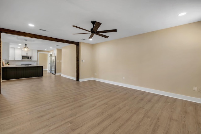 unfurnished living room featuring ceiling fan, light wood-type flooring, visible vents, and baseboards