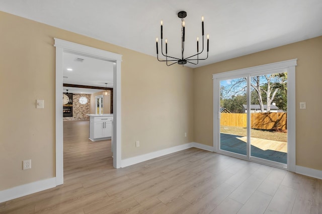 unfurnished dining area featuring light wood-type flooring, an inviting chandelier, and baseboards