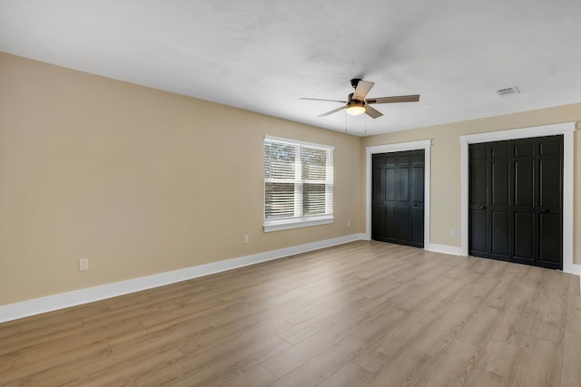 unfurnished bedroom featuring multiple closets, light wood-type flooring, ceiling fan, and baseboards