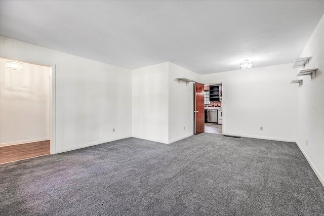 unfurnished room featuring visible vents, baseboards, and dark colored carpet