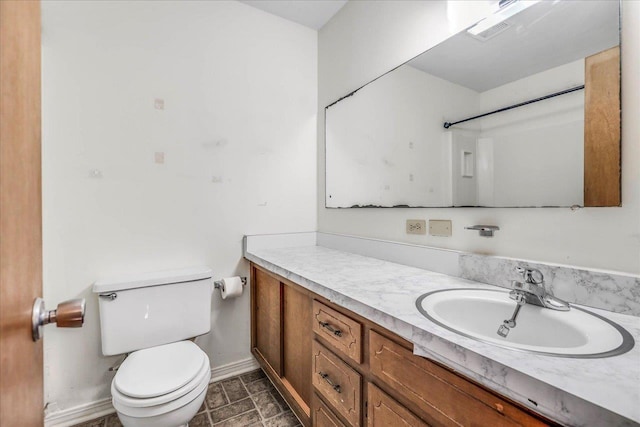 bathroom with toilet, visible vents, vanity, and baseboards