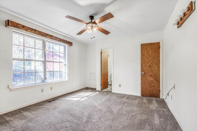 unfurnished bedroom with carpet floors, a ceiling fan, visible vents, baseboards, and ensuite bath