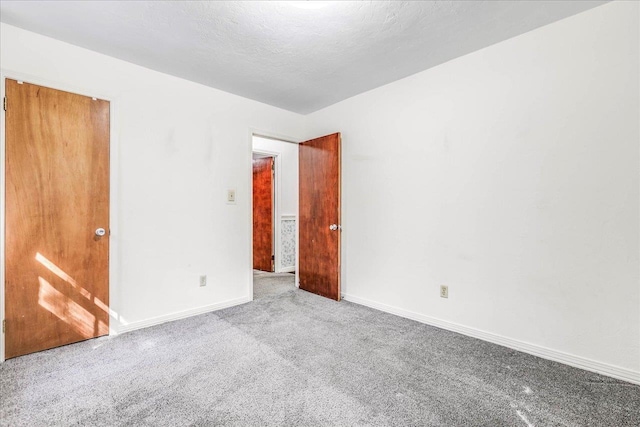 carpeted empty room with a textured ceiling and baseboards