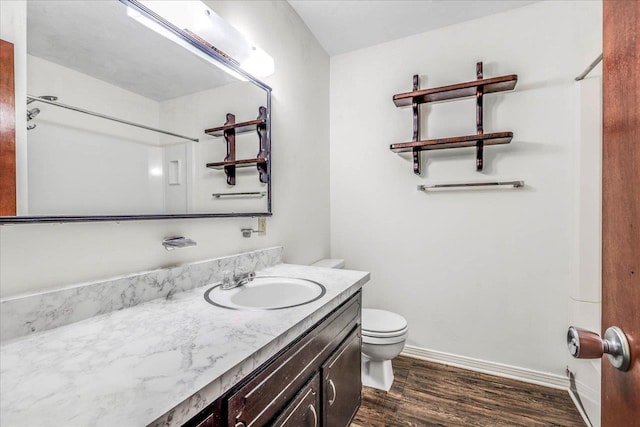 full bath with toilet, baseboards, wood finished floors, and vanity