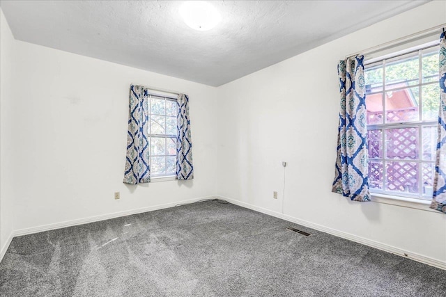 carpeted empty room with a textured ceiling, visible vents, and baseboards