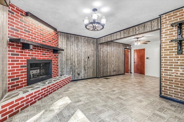 unfurnished living room featuring a brick fireplace, wood walls, brick patterned floor, and ceiling fan